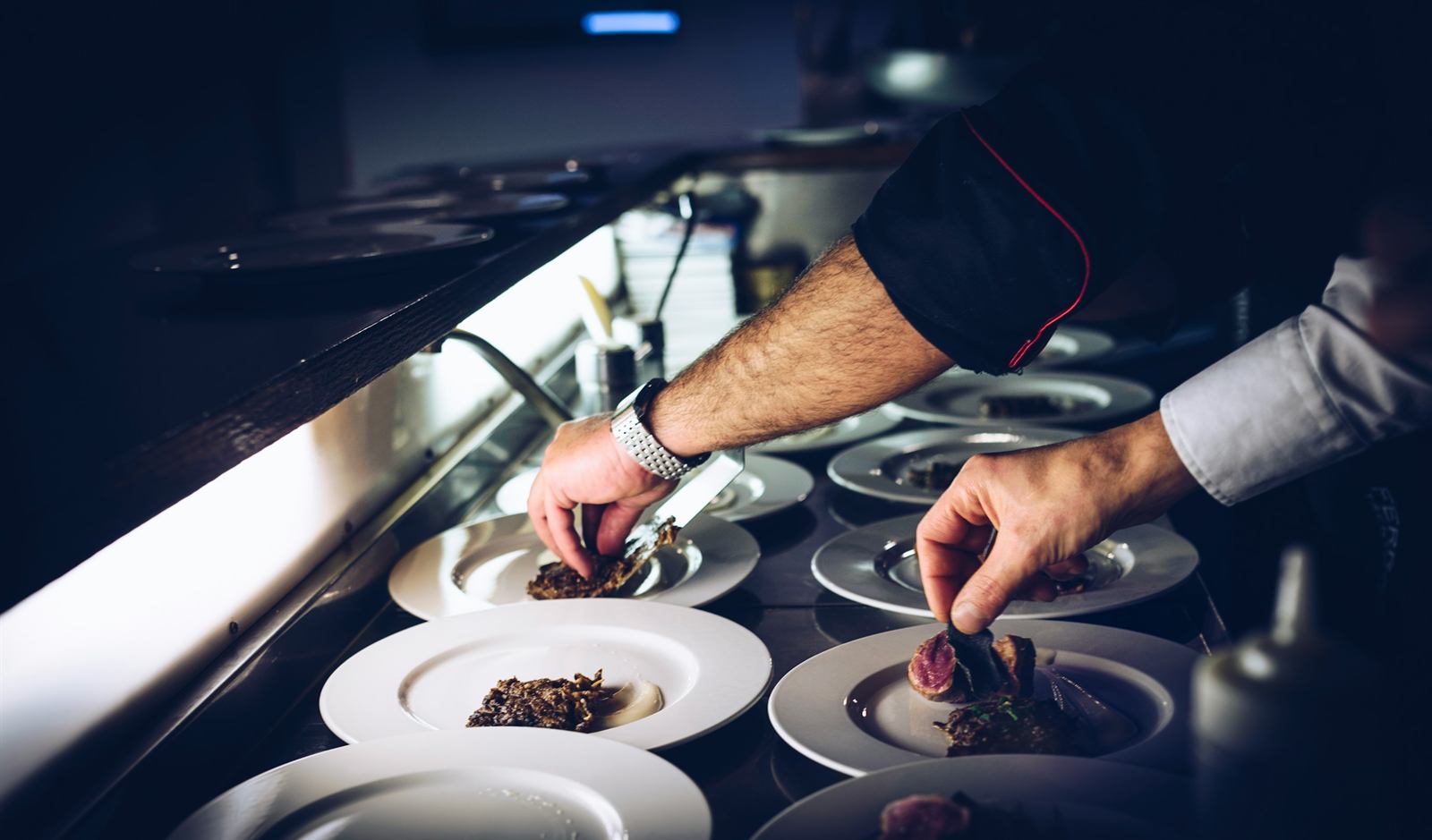 Chef plating a finished dish at the kitchen pass